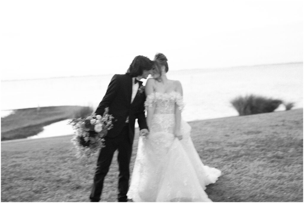 Black and white image of the bride and groom by the ocean 